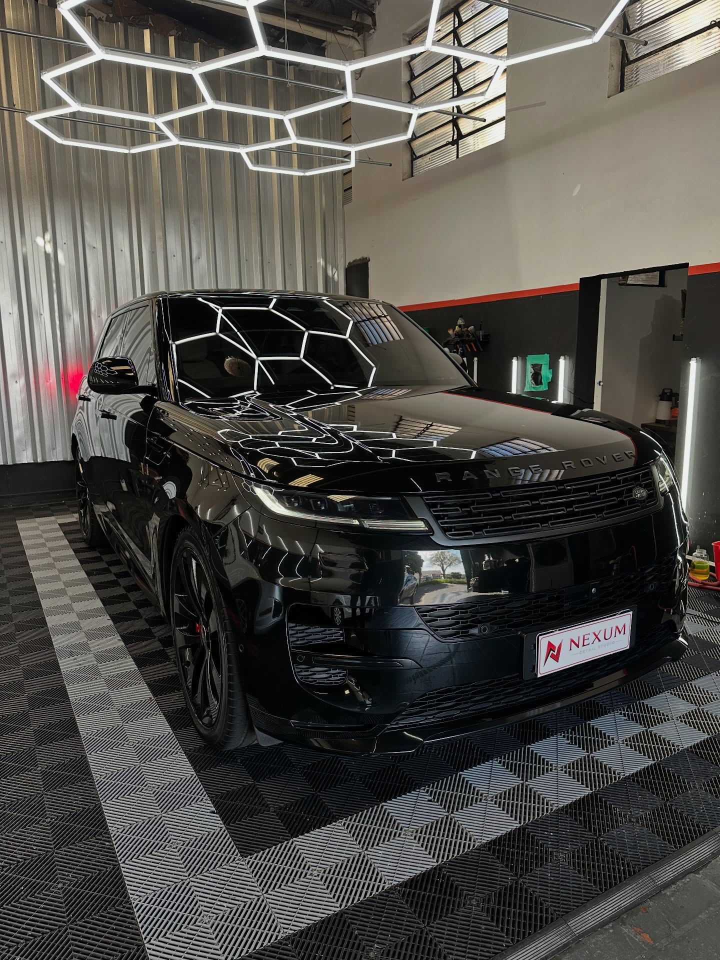 Range Rover preto com coating cerâmico refletindo as luzes hexagonais
